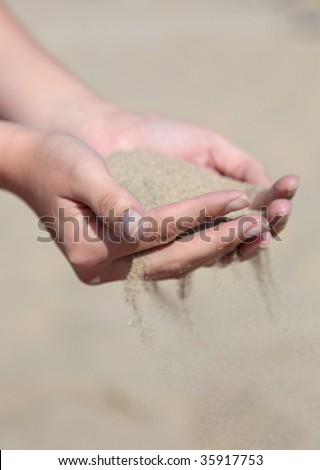 A person holding dry sand in his hands.