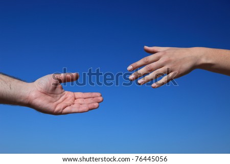 Two persons trying to reach hands. All in front of bright blue sky.