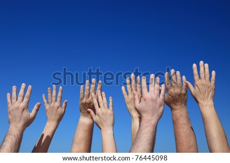 Various hands reaching to the bright blue sky
