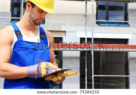 Manual worker on construction site writing on clipboard.