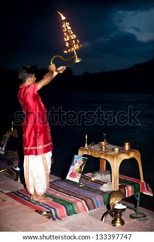 RISHIKESH, INDIA - AUGUST 28: Young Hindu Bramin performs religious fire ritual of worshipping during the daily ceremony called \