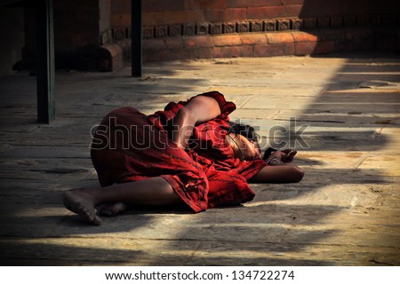 KATHMANDU, NEPAL - NOVEMBER 1: Poor unidentified nepalese woman sleeps on stone floor in a yard of buddhist temple on November 1, 2009 in Kathmandu