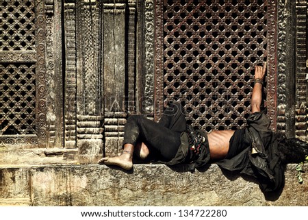 BHAKTAPUR, NEPAL - NOVEMBER 13: Poor unidentified nepalese man sleeps on stone step of hindu temple on November 13, 2009 in Bhaktapur