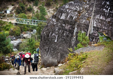 CHHEPLUNG, NEPAL - NOVEMBER 3: Group of trekkers moves up slowly along the mountain path in the valley of Dudh Kosi river on November 3, 2013 in Chheplung