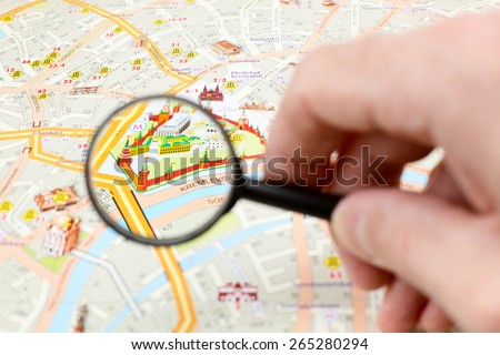 Man is examining Moscow city map with magnifying glass - focus on Moscow Kremlin