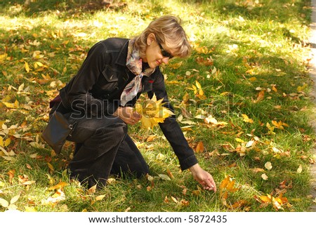 Young woman picking up autumn leaves