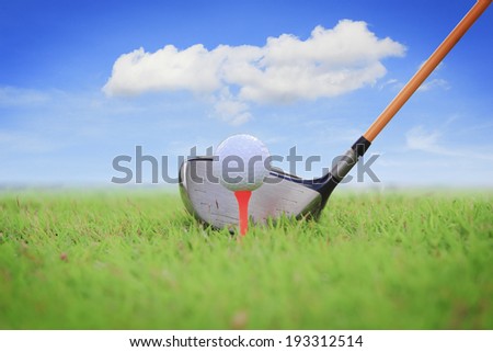Golf club and ball in grass with blue sky