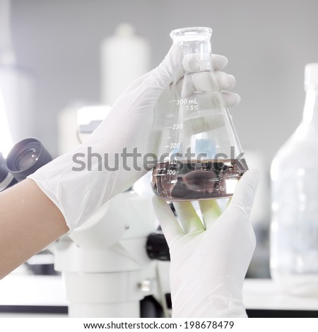 a chemist holding a tube with liquid in lab