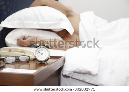 sleeping man disturbed by alarm clock