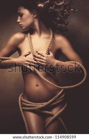beautiful naked young woman with a rope around the body, studio shot