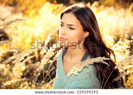 young woman standing in golden field looking at the sky