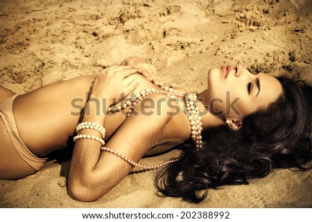 beautiful woman lying on the golden sand, outdoor portrait