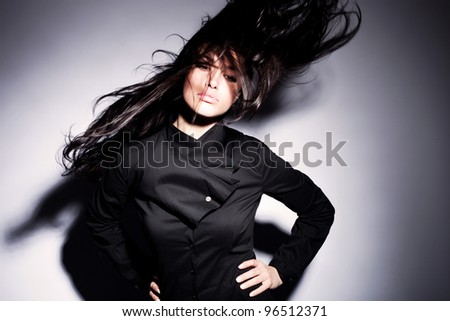 young woman in elegant black shirt with hair in motion, studio shot