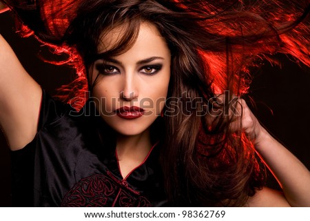 wild beauty with long flying hair and red back light, studio dark