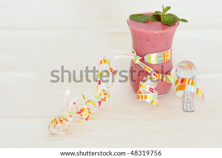 Glass with the cowberry mousse, decorated with mint leaves, and a small spoon on a beige cloth