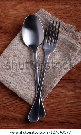 spoon and fork with napkin on wooden table