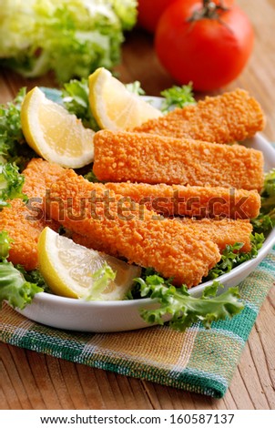 crispy fish sticks with vegetables and lemon slices
