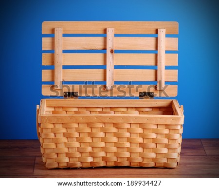 empty picnic basket on the wooden table with blue background