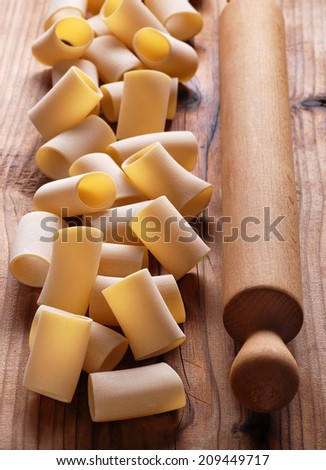 Paccheri raw on the wooden table, traditional Neapolitan pasta