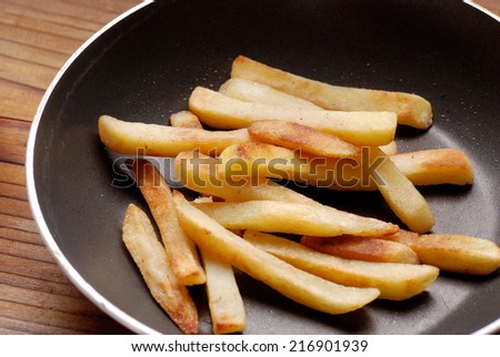 french fries in the pan on the wooden table