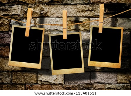 Old picture frame hanging on clothesline on grunge wall.