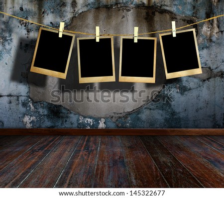 Old picture frame hanging on clothesline in grunge room.