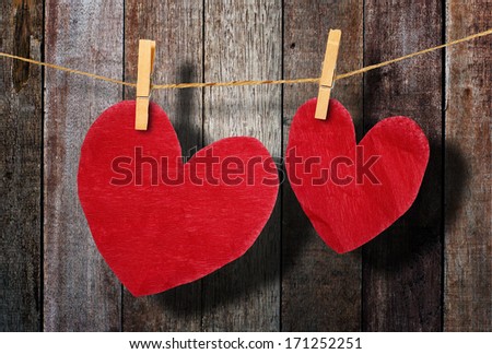 Red heart  hanging on clothesline on wood background.