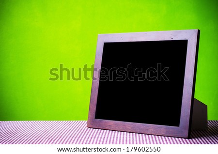 Blank picture frame put on tablecloth in green wallpaper room.