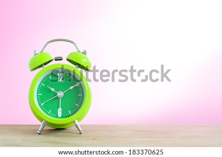 Alarm clock put on the wooden in pink wallpaper room.