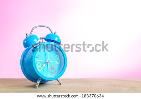 Alarm clock put on the wooden in pink wallpaper room.