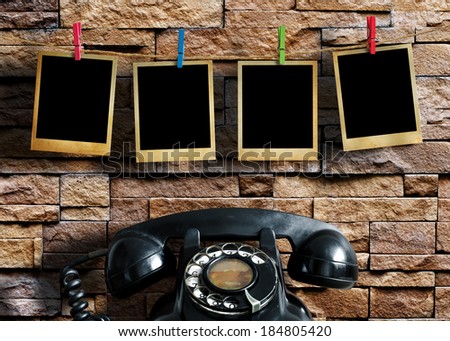 Old picture frame hanging on clothesline and old telephone on grunge background.