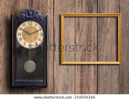 Old clock and empty picture frame on wood wall.