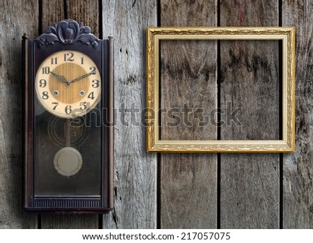 Old clock and empty picture frame on wood wall.