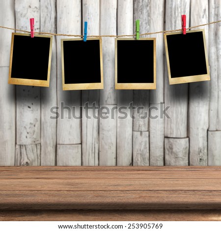 Old picture frame hanging on clothesline on wood background.