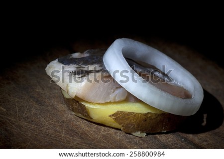 Piece of salted herring on slice of boiled jacket potato