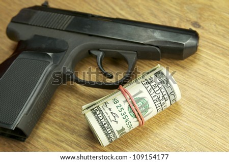 dollars and a gun on the wooden table