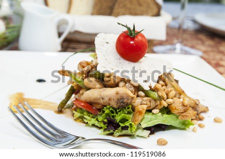warm salad of vegetables and meat on a plate in a restaurant
