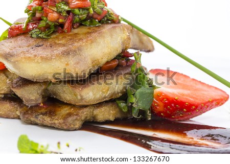 Roast goose liver is decorated with greens and strawberries