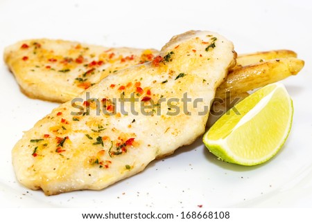 sturgeon steak cooking on the grill with lemon and sauce on a table in a restauran