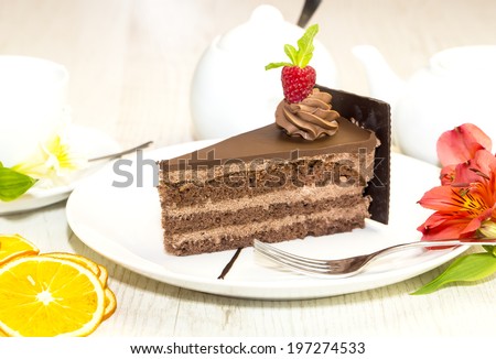 Prague piece of cake decorated with raspberries on a white background