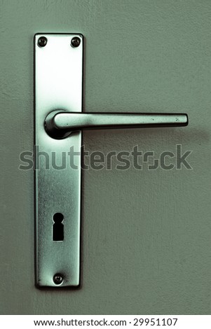 frontal view of a clean metal doorhandle on a bright painted door