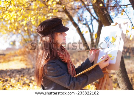The girl is engaged in painting on nature