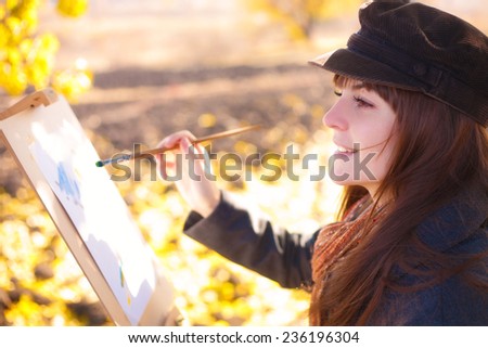 The girl draws on nature autumn landscape
