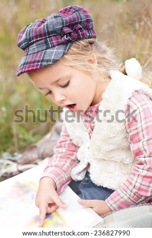 Little girl reading book on nature