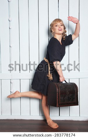Pretty woman with a suitcase in his hand waving