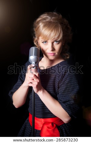 A beautiful girl with a microphone on stage, black background