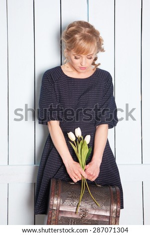 Pretty woman with flowers in her hand and a suitcase