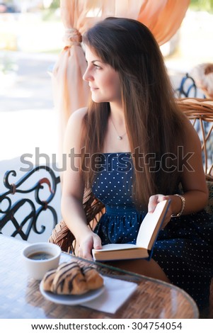 Young beautiful woman reading a book in the cafe