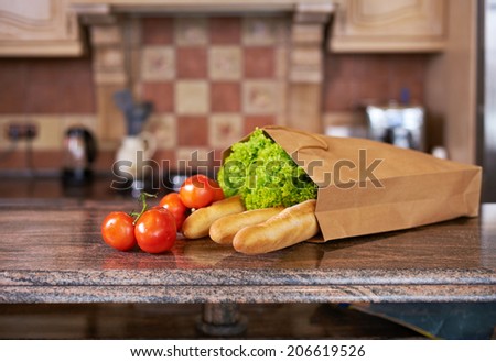 paper bag with salad, tomatoes and bread in the kitchen