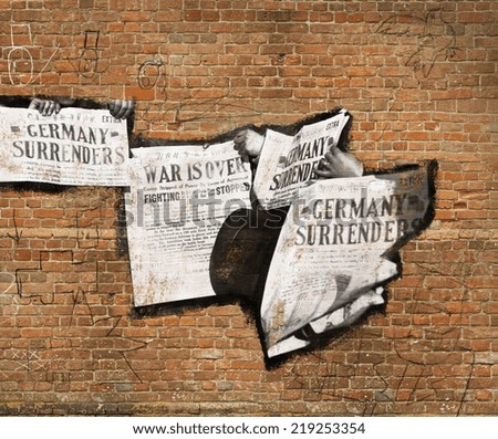 Image of newspapers on a brick wall with graffiti